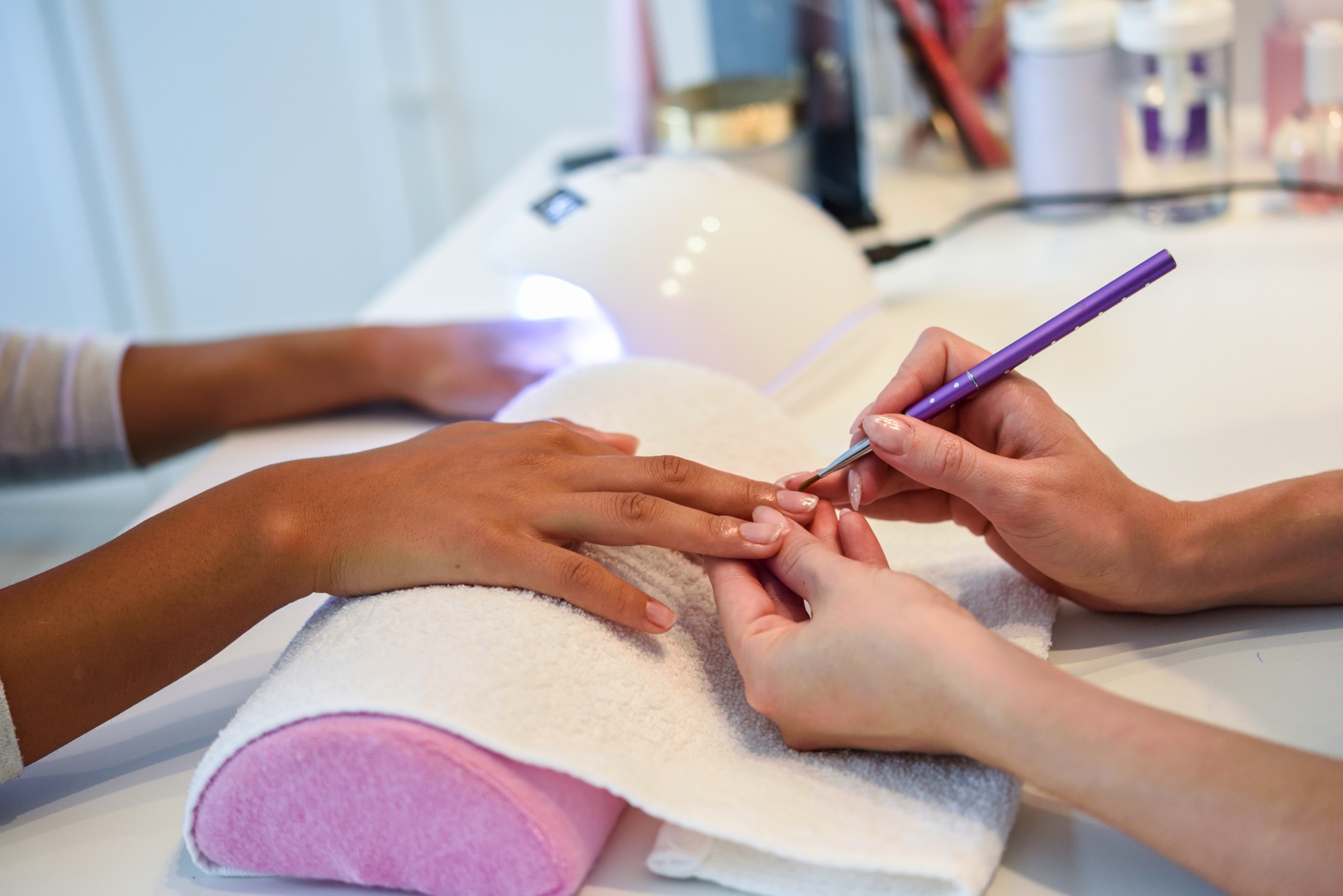 close-up-beautician-painting-woman-s-nails-with-brush-nail-salon